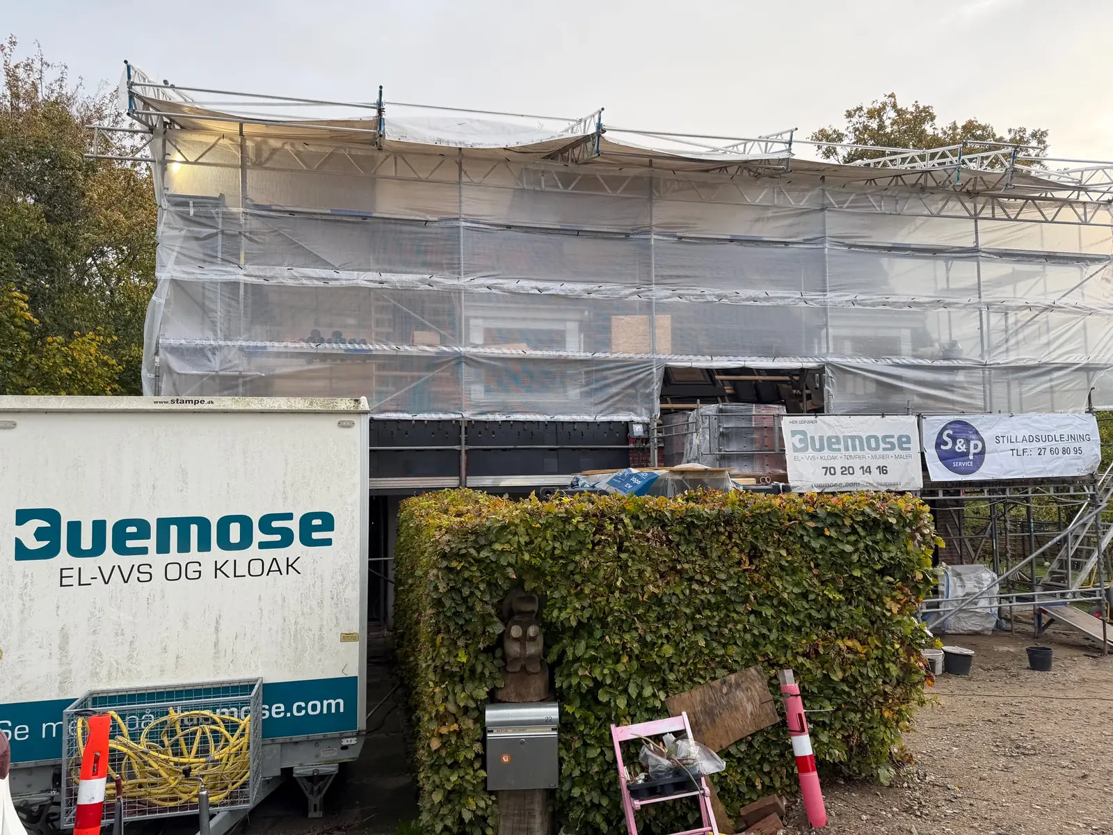 Boligen pakket ind i stillads og vejrlukning under byggeprocessen, med Duemoses trailer foran